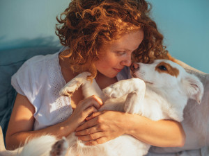 A woman holding her dog close. 