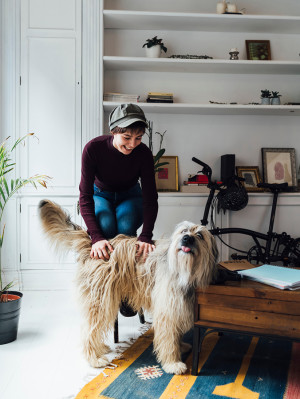 Happy young female student playing with hairy dog at home
