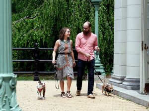 Couple walks their dogs on a date outside at the park.