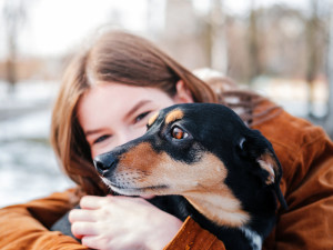 Woman holding her scared dog outside.