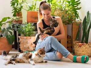 Woman petting her two cats at home.