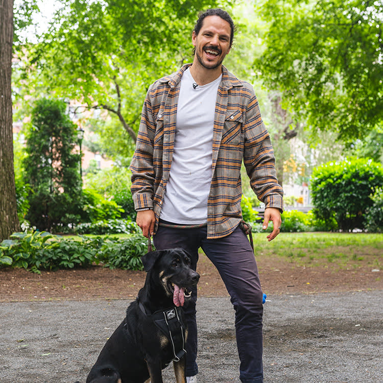 celebrity chef dan churchill smiling at his dog at an outdoor market in the city. 